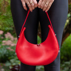Selena red vegan leather hobo bag held by model outdoors